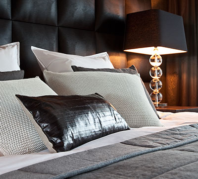 opgemaakt bed met gebreide raffia en visleren sierkussens